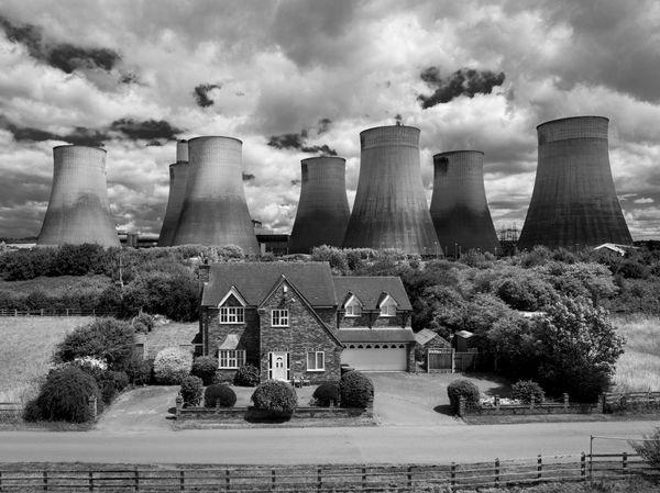 Ratcliffe power station looms behind a picturesque house whith dramatic clouds in the background 